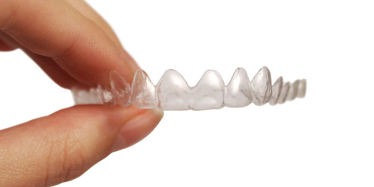 Person holding a custom, transparent Invisalign® device.