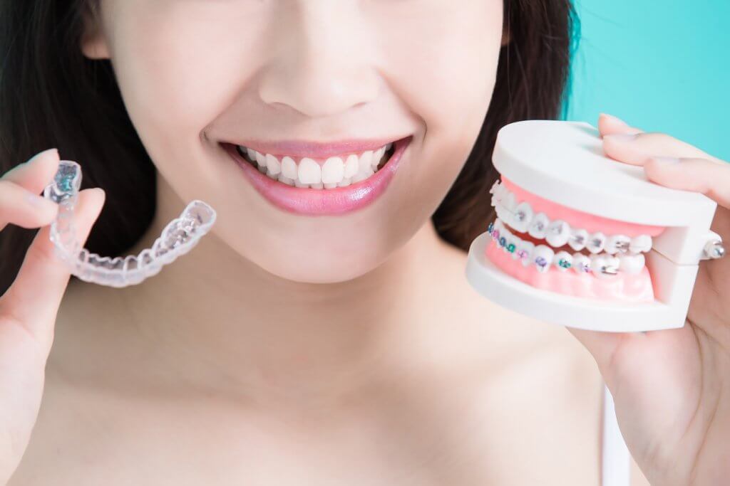 Closeup of woman holding models of Invisalign® and Braces