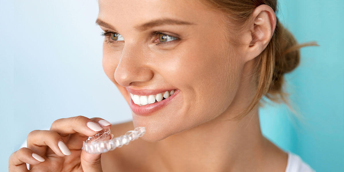 Woman smiling and holding Invisalign