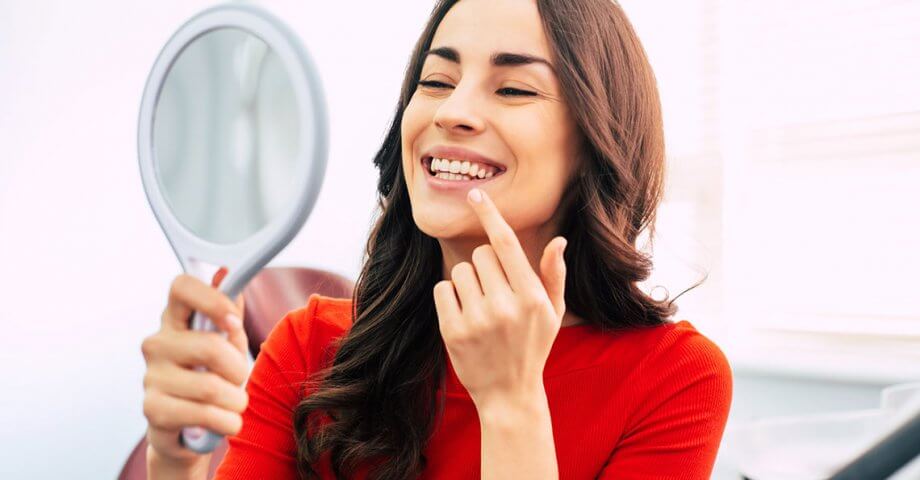 Smiling woman holding up mirror