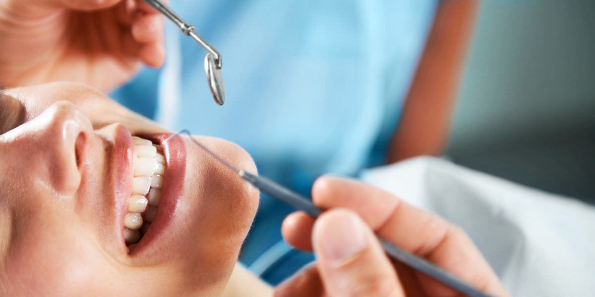 Woman smiling in dentist chair while being examined.